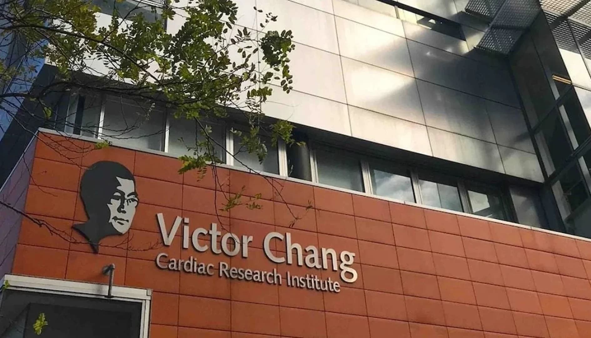 Facade of the Victor Chang Cardiac Research Institute building, featuring an orange tiled wall with the institute’s name and a stylized silhouette logo.